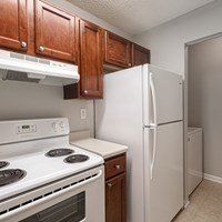 A white stove and refrigerator in a kitchen with brown cabinets.
