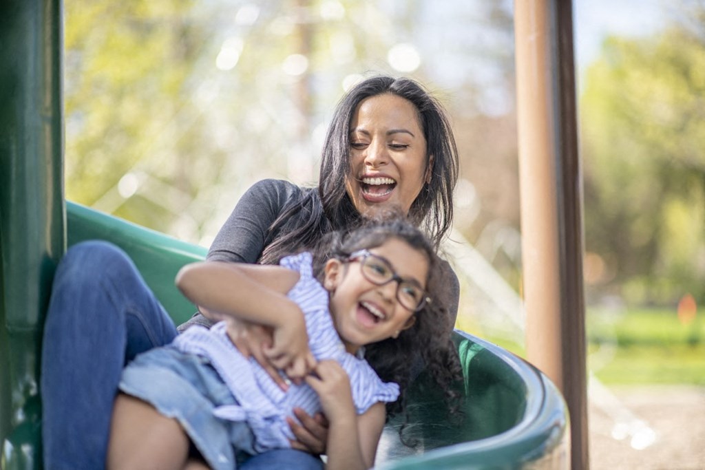 a mother and daughter laughing on a playground slide