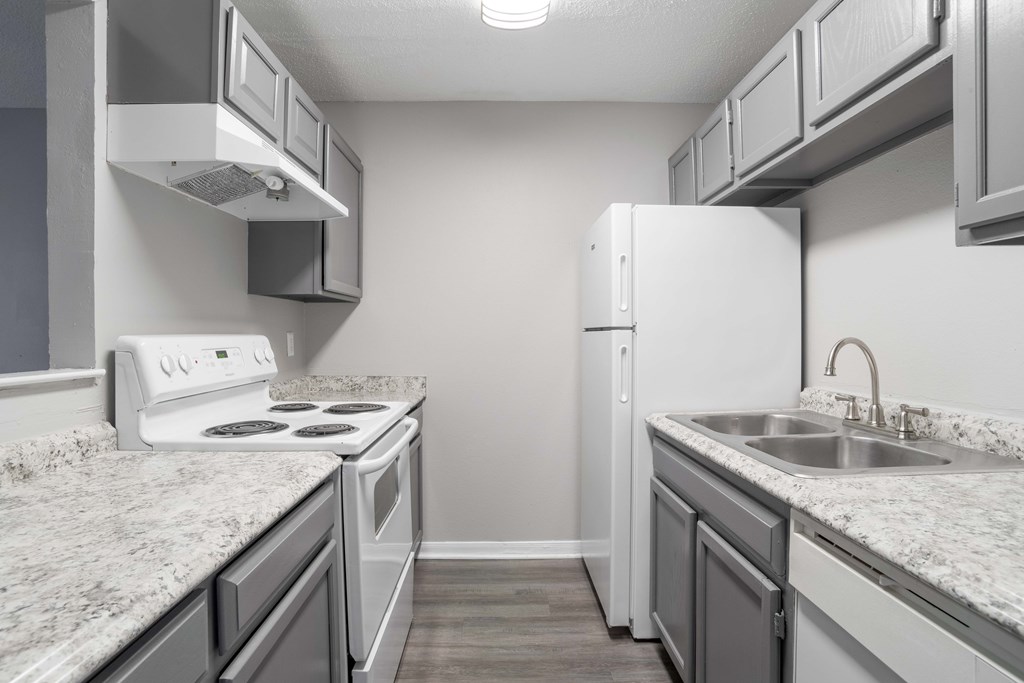 A kitchen with a white stove and a white refrigerator.