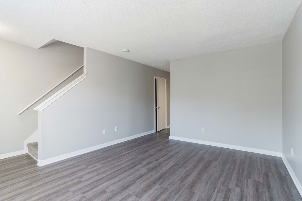 A room with a wooden floor and a staircase leading to the upper floor.
