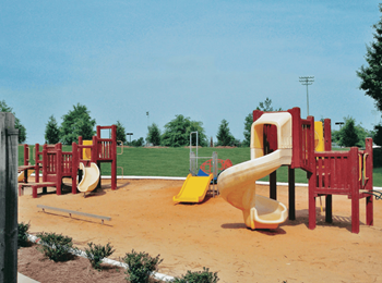 A playground with a yellow slide and red chairs.