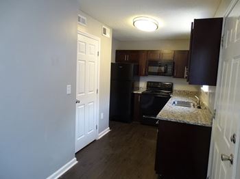 A kitchen with a black refrigerator and wooden cabinets.