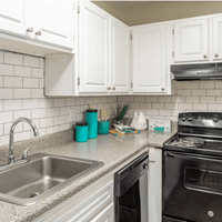 A kitchen with white cabinets and a black stove.