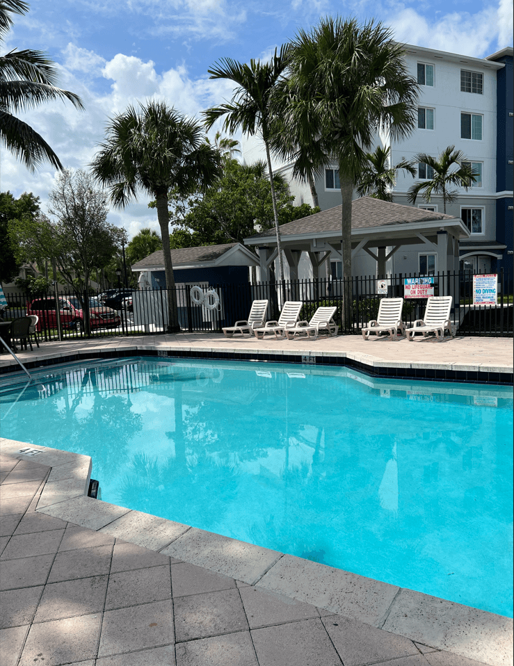 a large swimming pool with palm trees in front of a building