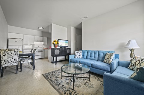 A living room with a blue couch and a glass table.