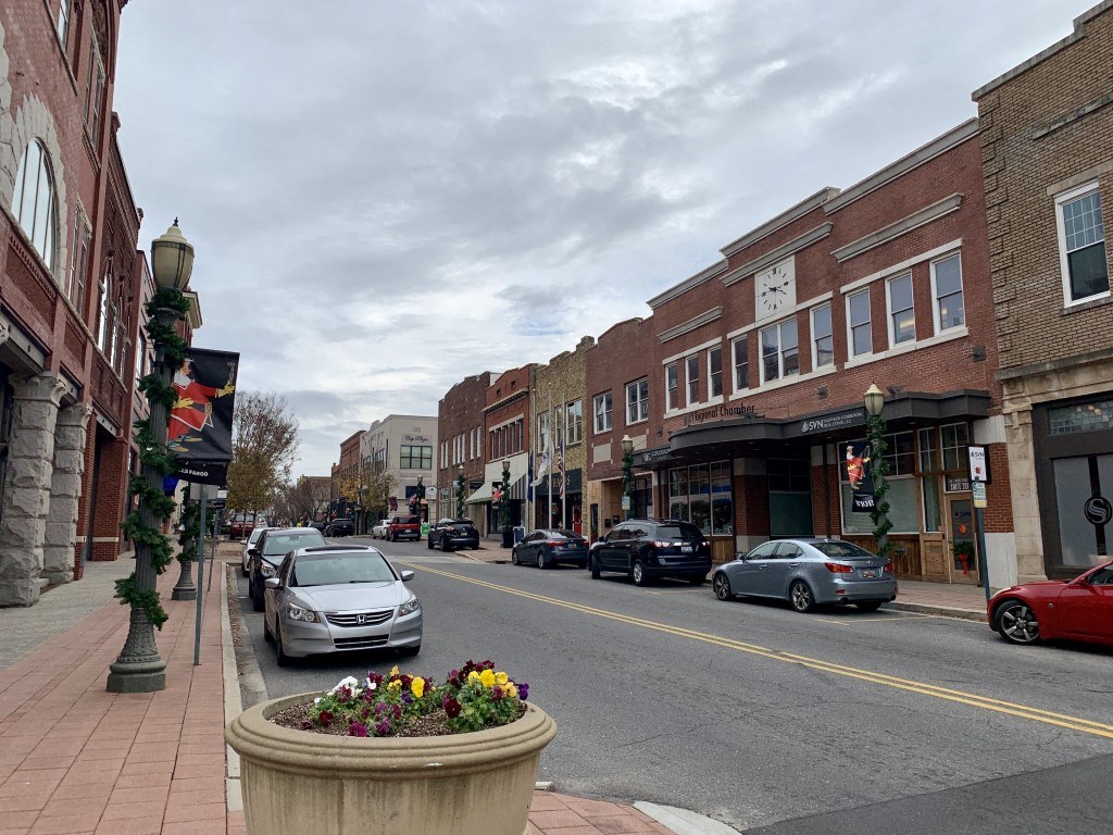 a city street with cars and a large pot of flowers