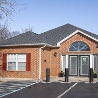 A small brick building with a black roof and a glass door.
