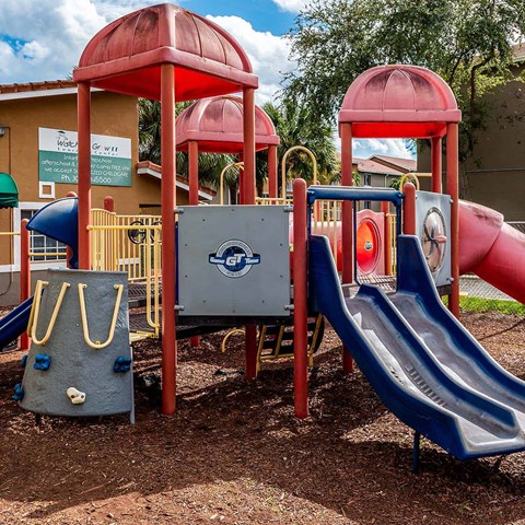 A playground with a blue slide and a red structure.