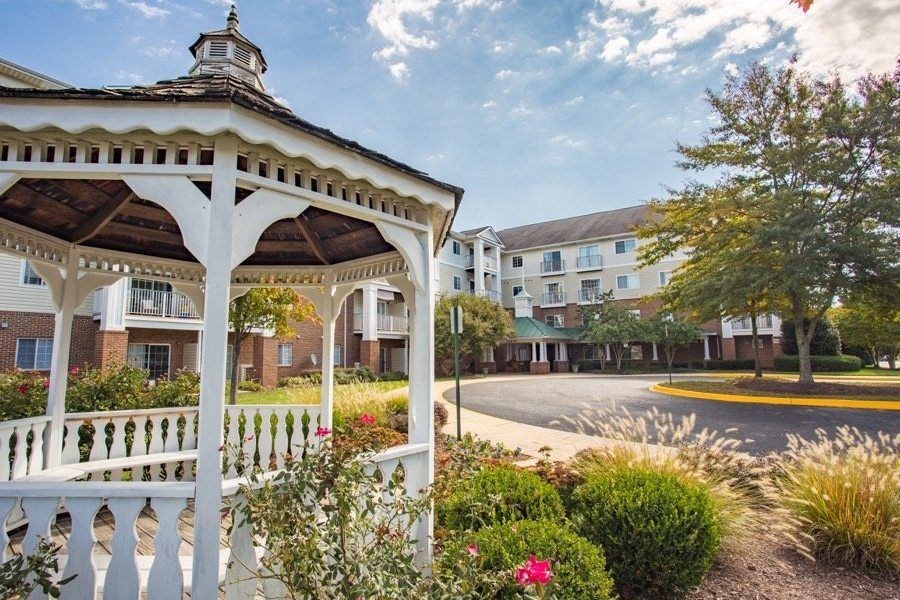 A gazebo is in the foreground of a street with apartment buildings in the background.