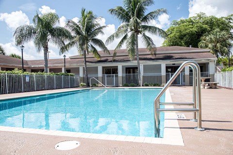 A swimming pool surrounded by palm trees and a building in the background.