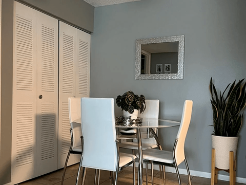 A dining room with a table, chairs and a mirror.