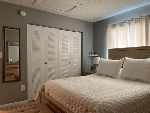 A bedroom with a large bed and a mirror on the wall.