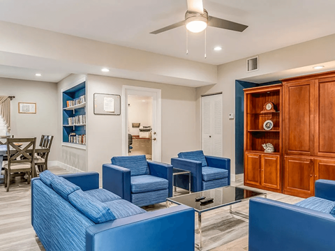 A living room with blue chairs and a wooden cabinet.