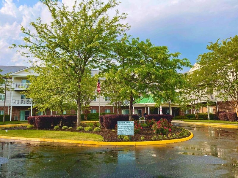 a roundabout with trees and a sign in front of a building at Greenbrier Seniors Apartments, Chesapeake, 23320  