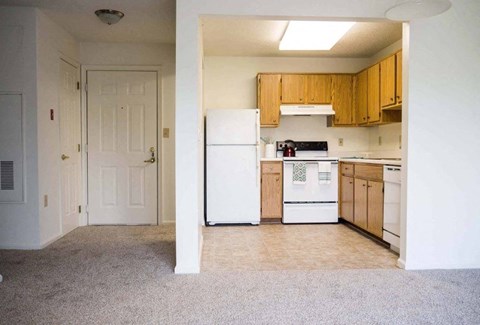 an empty kitchen with white appliances and wooden cabinets at Greenbrier Seniors Apartments, Chesapeake, Virginia