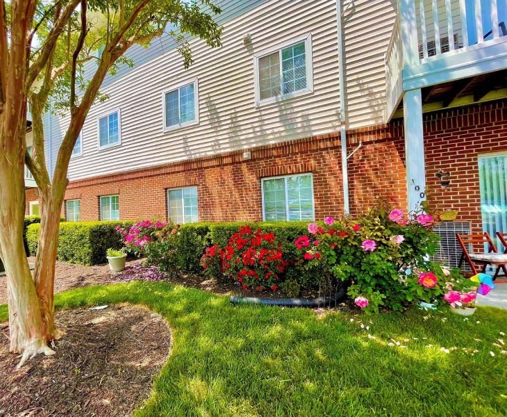 the front yard of an apartment building with flowers and grass at Greenbrier Seniors Apartments, Chesapeake 