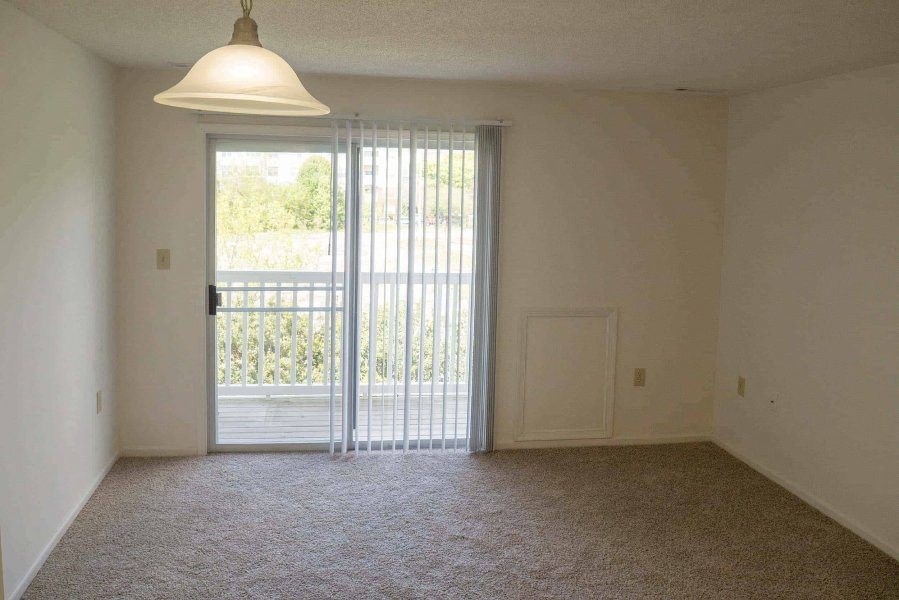 an empty living room with a door to a balcony at Greenbrier Seniors Apartments, Chesapeake, VA  