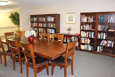 A dining room with a table surrounded by chairs and a bookshelf filled with books.