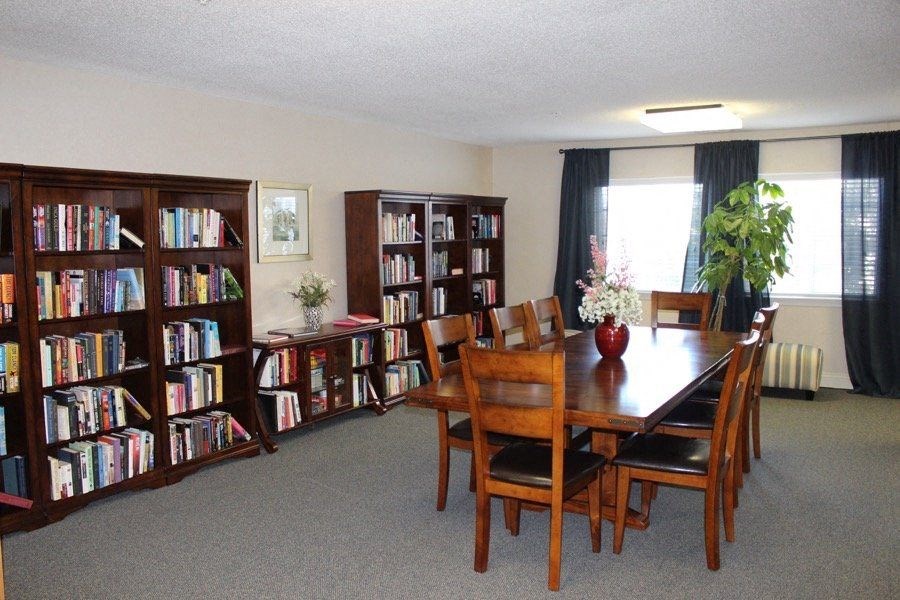 a dining room with a table and chairs and bookshelves at Greenbrier Seniors Apartments, Chesapeake, VA  