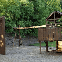 A wooden swing set sits in a backyard.