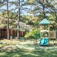 A playground with a green slide and a wooden structure.