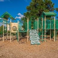A playground with a green slide and a yellow structure.