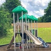 A playground with a green slide and a red ball.