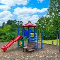 A playground with a red slide and a blue structure.