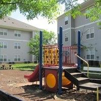 A playground with a red slide and a yellow and red playhouse.