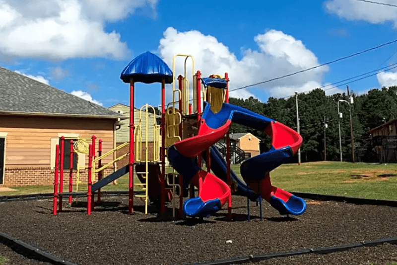 A playground with a blue slide and red and blue play equipment.