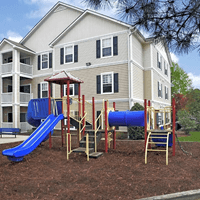 A playground in front of a large apartment building.