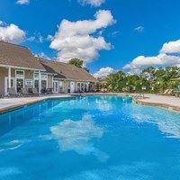A large swimming pool in front of a building with a clear blue sky above.