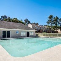 A large swimming pool in front of a building with a blue sky in the background.