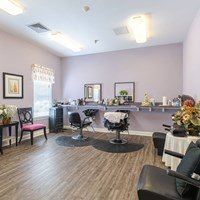 A room with purple walls and wooden flooring has a table with a white tablecloth and a vase of flowers on it.