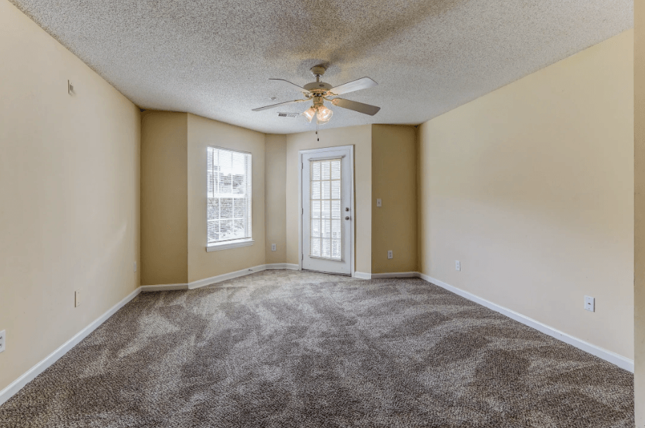 an empty living room with a ceiling fan