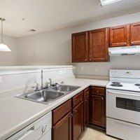 A kitchen with white appliances and brown cabinets.