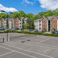Apartment buildings are in the background of a parking lot.