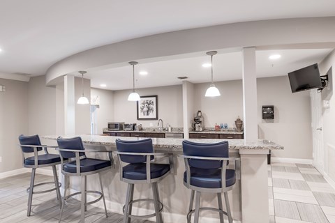 A kitchen with a bar area featuring blue chairs and a white counter.