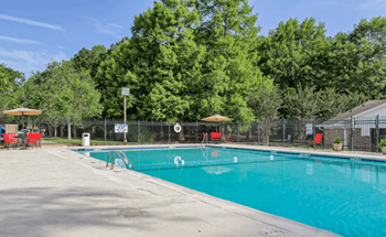 A swimming pool surrounded by trees and a fence with a signboard.