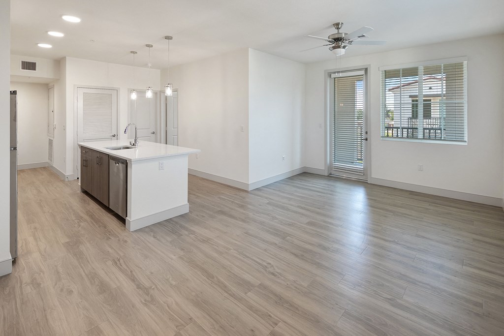 an empty kitchen and living room with white walls and wood flooring