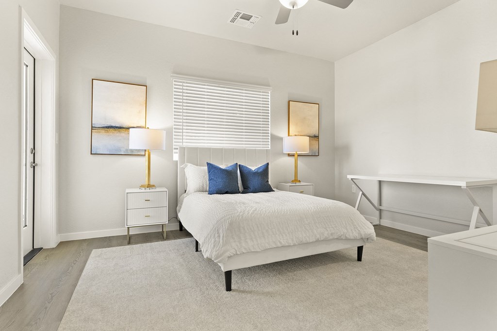 a bedroom with a bed and a desk with two lamps