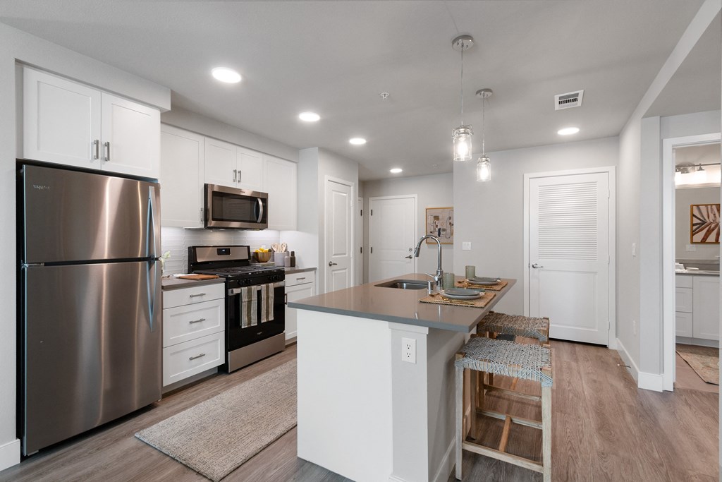 a large kitchen with stainless steel appliances and white cabinets