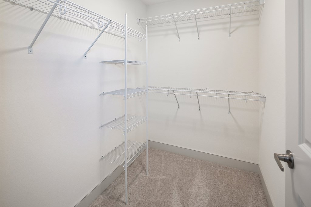 a white closet with empty shelves in a room with a door