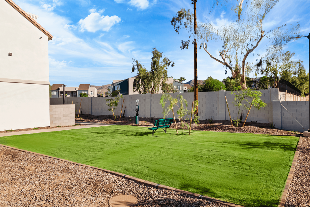 a backyard with a green lawn and a bench