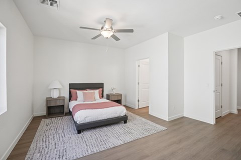 A bedroom with a bed, nightstands, and a ceiling fan.