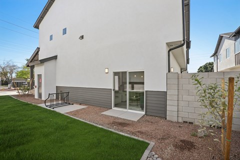 A modern house with a grey exterior and a small garden in front.