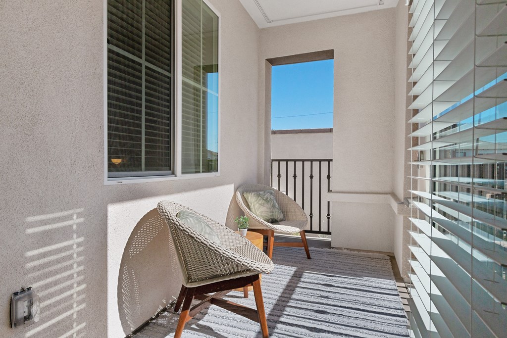 a balcony with two chairs and a window