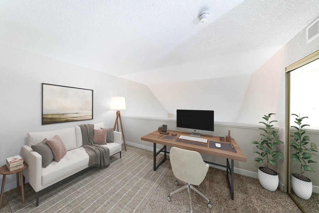 a living room with a couch and a desk with a computer