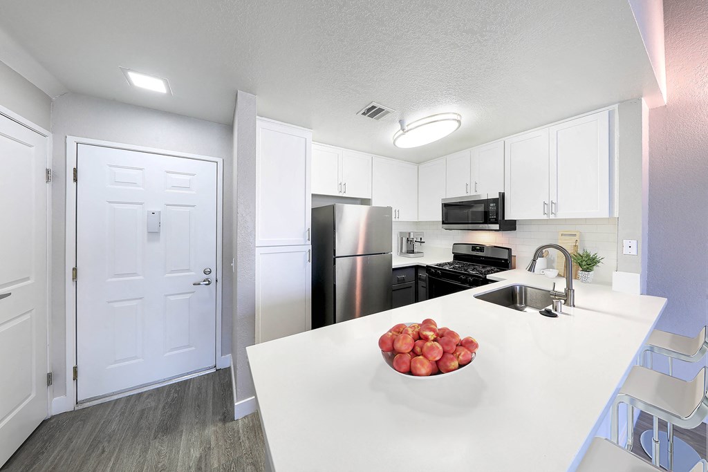 a kitchen with a white counter top and a stainless steel refrigerator