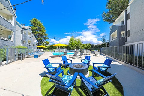 an outdoor patio with blue chairs and a fire pit